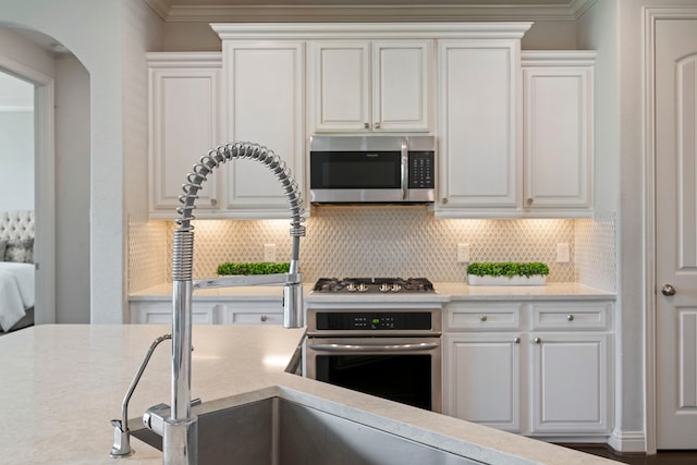 18735 Evanhale Bend Dr, Cypress, TX 77429 - kitchen with stainless steel appliances, ornamental molding, tasteful backsplash, white cabinets, and arched walkways