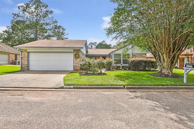 12121 Maverick Dr, Willis, TX 77378 - view of front of home with driveway, brick siding, a front yard, and a garage
