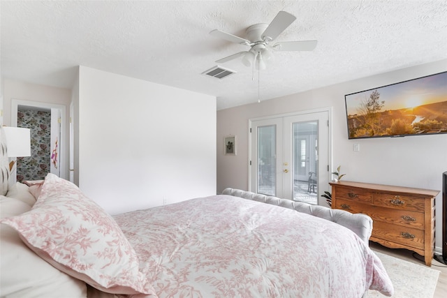 12121 Maverick Dr, Willis, TX 77378 - bedroom with french doors, a textured ceiling, a ceiling fan, and wood finished floors