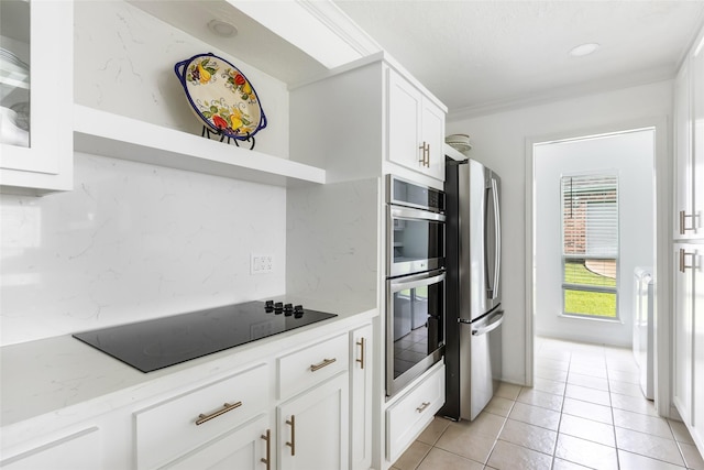 12121 Maverick Dr, Willis, TX 77378 - kitchen featuring stainless steel appliances, white cabinetry, light tile patterned floors, crown molding, and decorative backsplash