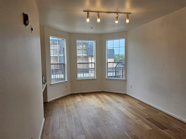7575 Kirby Dr Unit 1104, Houston, TX 77030 - unfurnished room with wood-type flooring, healthy amount of natural light, baseboards, and track lighting