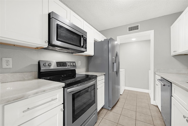 8385 Sands Point Dr Unit 5, Houston, TX 77036 - kitchen with appliances with stainless steel finishes, white cabinets, light tile patterned floors, a textured ceiling, and baseboards