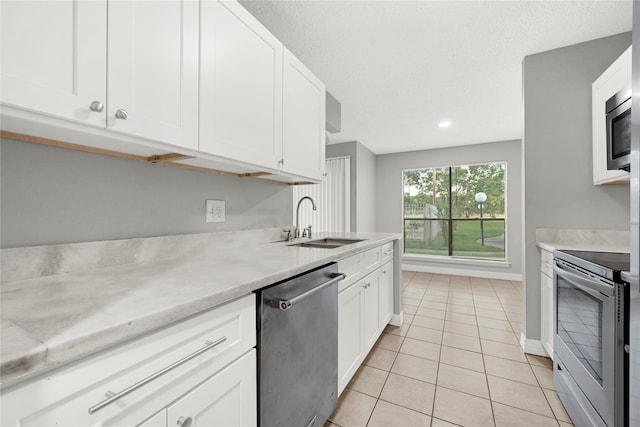 8385 Sands Point Dr Unit 5, Houston, TX 77036 - kitchen featuring stainless steel appliances, a sink, light countertops, light tile patterned flooring, and white cabinets