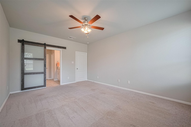 31630 Heguy Pass, Fulshear, TX 77441 - unfurnished bedroom with a barn door, baseboards, light colored carpet, ensuite bath, and a ceiling fan