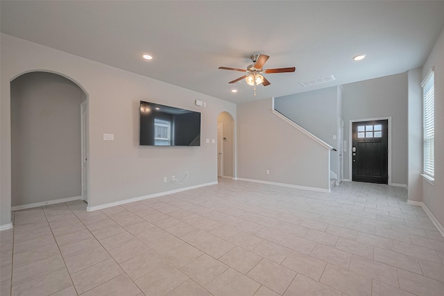 31630 Heguy Pass, Fulshear, TX 77441 - unfurnished living room featuring arched walkways, ceiling fan, recessed lighting, light tile patterned floors, and stairs