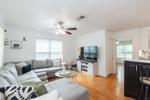 6840 County Road 659, Brazoria, TX 77422 - living room with a ceiling fan, light wood-type flooring, wood walls, a textured ceiling, and crown molding