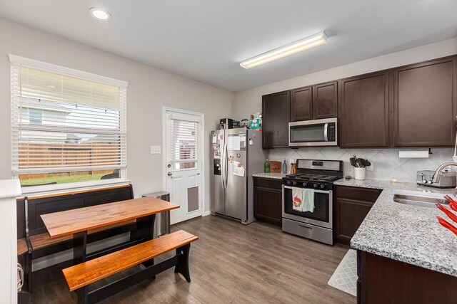 25131 Bells Canyon Dr, Porter, TX 77365 - kitchen featuring stainless steel appliances, a sink, dark brown cabinets, backsplash, and wood finished floors