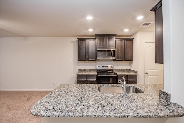 10699 Lost Maples Dr, Cleveland, TX 77328 - kitchen featuring stainless steel appliances, a sink, dark brown cabinetry, light stone countertops, and carpet floors