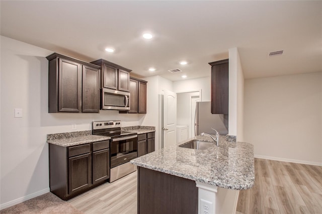10699 Lost Maples Dr, Cleveland, TX 77328 - kitchen featuring appliances with stainless steel finishes, a sink, dark brown cabinets, baseboards, and light wood finished floors