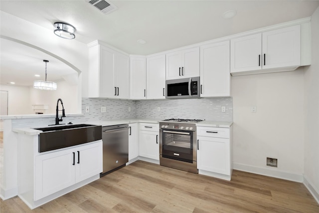 5847 Southington St, Houston, TX 77033 - kitchen with appliances with stainless steel finishes, light wood-type flooring, backsplash, light countertops, and a peninsula