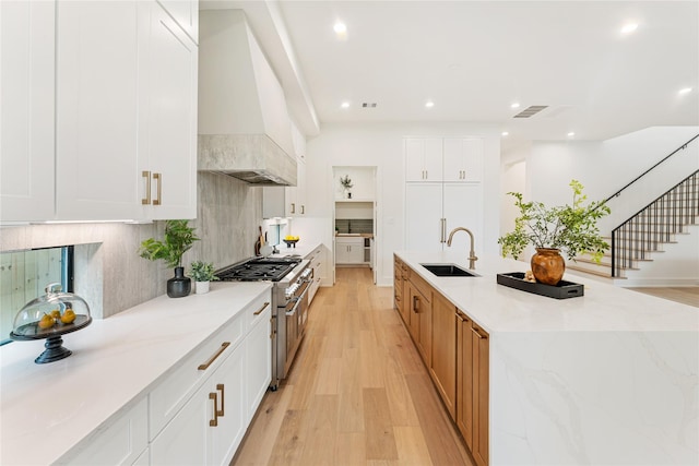1741 Chippendale Rd, Houston, TX 77018 - kitchen with stainless steel range, premium range hood, light wood-style floors, backsplash, and a large island with sink
