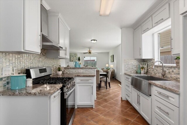 8702 Cold Lake Dr, Houston, TX 77088 - kitchen with stainless steel range with gas stovetop, a sink, tasteful backsplash, tile patterned floors, and white cabinetry