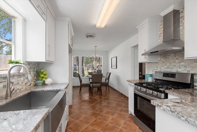 8702 Cold Lake Dr, Houston, TX 77088 - kitchen with stainless steel range with gas cooktop, wall chimney exhaust hood, a sink, decorative backsplash, and white cabinets
