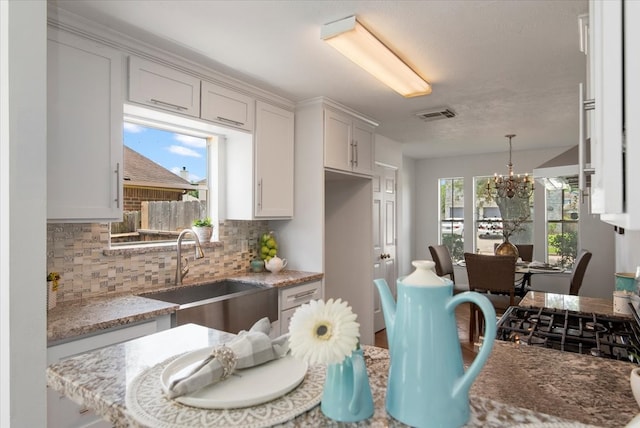 8702 Cold Lake Dr, Houston, TX 77088 - kitchen with a sink, a chandelier, backsplash, light stone countertops, and hanging light fixtures