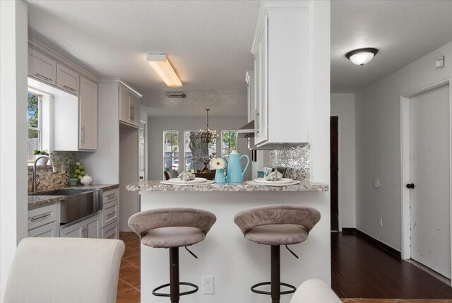 8702 Cold Lake Dr, Houston, TX 77088 - kitchen with a sink, decorative backsplash, a peninsula, and a kitchen bar