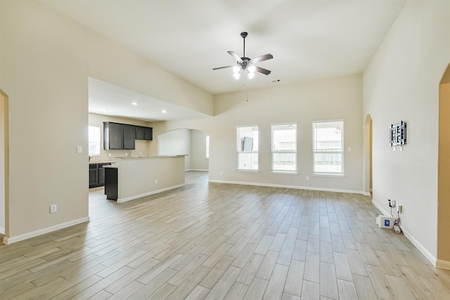 22303 Bauer Garden Dr, Hockley, TX 77447 - unfurnished living room featuring arched walkways, ceiling fan, light wood-style flooring, recessed lighting, and baseboards