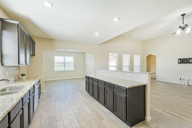 22303 Bauer Garden Dr, Hockley, TX 77447 - kitchen with a sink, arched walkways, baseboards, a kitchen island, and vaulted ceiling