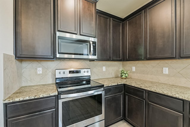 22303 Bauer Garden Dr, Hockley, TX 77447 - kitchen featuring appliances with stainless steel finishes, dark brown cabinets, light stone countertops, and decorative backsplash