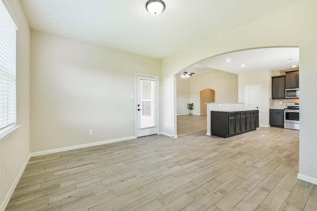 22303 Bauer Garden Dr, Hockley, TX 77447 - kitchen with stainless steel appliances, open floor plan, arched walkways, light wood-style flooring, and ceiling fan