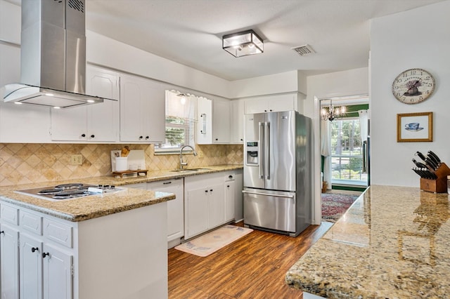 915 Timber Cove Dr, Seabrook, TX 77586 - kitchen featuring appliances with stainless steel finishes, wall chimney range hood, dark wood-style flooring, and white cabinetry