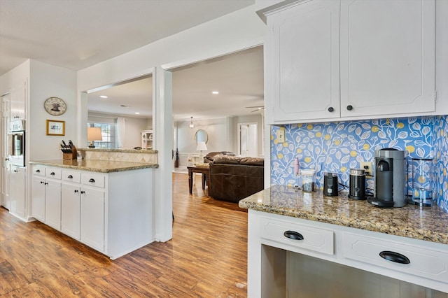 915 Timber Cove Dr, Seabrook, TX 77586 - kitchen featuring light wood-type flooring, wall oven, recessed lighting, decorative backsplash, and white cabinets