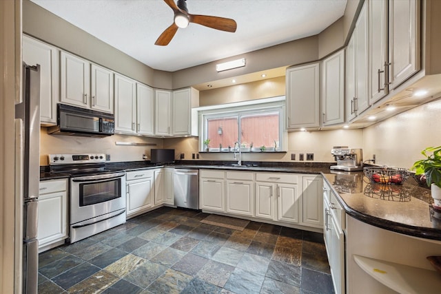 1112 Jackson Blvd, Houston, TX 77006 - kitchen featuring stainless steel appliances, dark countertops, stone tile flooring, ceiling fan, and white cabinetry