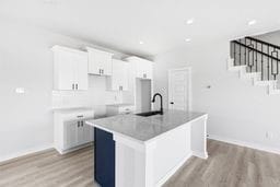 6418 Bolinas Ct, Rosharon, TX 77583 - kitchen with a sink, light wood finished floors, a center island with sink, white cabinets, and recessed lighting