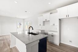 6418 Bolinas Ct, Rosharon, TX 77583 - kitchen with a center island with sink, wood finished floors, white cabinetry, a sink, and baseboards