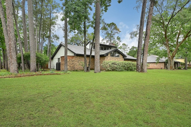 2003 Hidden Creek Dr, Houston, TX 77339 - view of side of property with central AC unit, a yard, a chimney, and brick siding