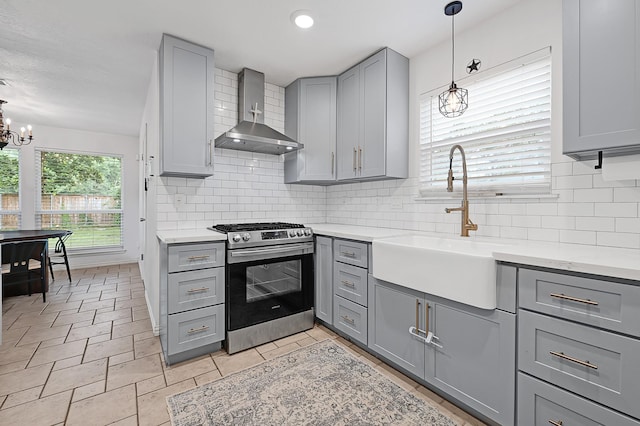 2003 Hidden Creek Dr, Houston, TX 77339 - kitchen featuring gray cabinets, stainless steel gas stove, wall chimney range hood, a sink, and a chandelier