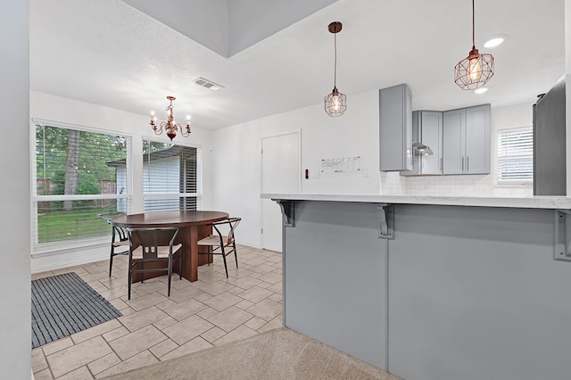 2003 Hidden Creek Dr, Houston, TX 77339 - kitchen featuring gray cabinetry, a chandelier, tasteful backsplash, a breakfast bar area, and decorative light fixtures