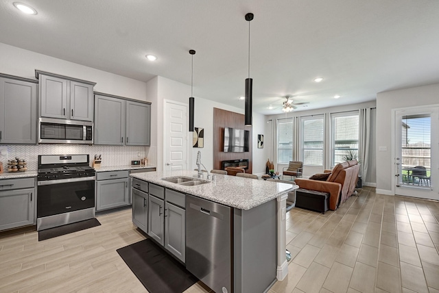 2104 Terra Rose Dr, Katy, TX 77493 - kitchen featuring stainless steel appliances, gray cabinetry, a sink, light wood finished floors, and tasteful backsplash