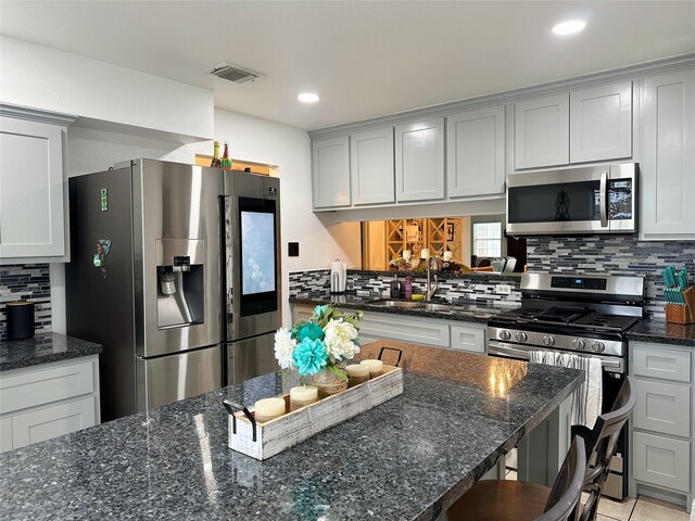 117 Lasso St, Angleton, TX 77515 - kitchen with stainless steel appliances, a sink, tasteful backsplash, a breakfast bar area, and dark stone countertops