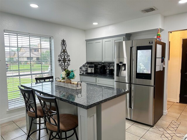 117 Lasso St, Angleton, TX 77515 - kitchen featuring stainless steel refrigerator with ice dispenser, light tile patterned floors, a breakfast bar area, dark stone counters, and recessed lighting