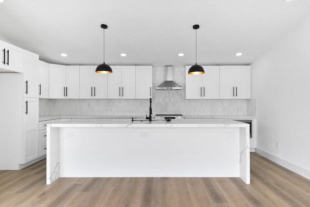 13014 John Reynolds Rd, Galveston, TX 77554 - kitchen featuring wall chimney range hood, decorative backsplash, light wood-style floors, an island with sink, and recessed lighting