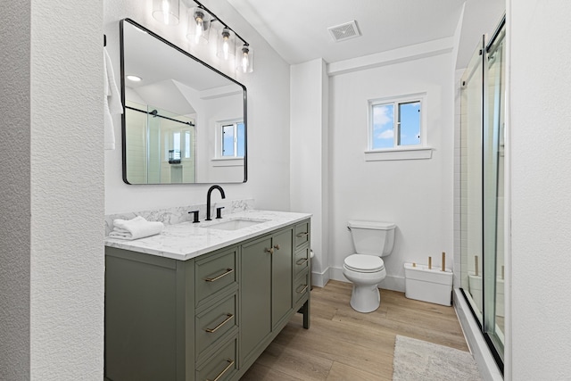 13014 John Reynolds Rd, Galveston, TX 77554 - full bathroom featuring vanity, toilet, a stall shower, and wood finished floors