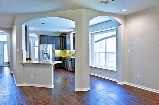 20610 Arrow Falls Ln, Richmond, TX 77407 - kitchen featuring a sink, appliances with stainless steel finishes, dark wood-type flooring, baseboards, and a peninsula