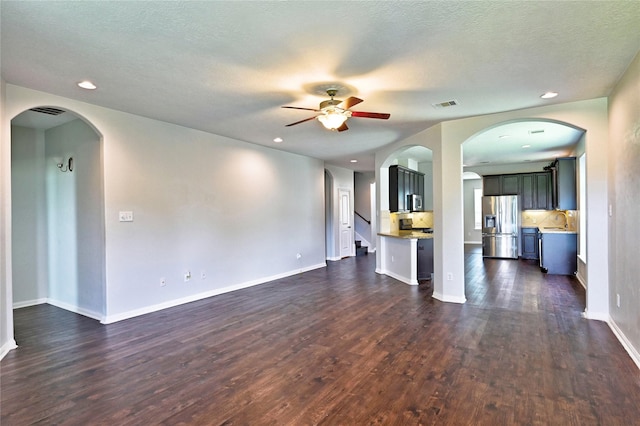 20610 Arrow Falls Ln, Richmond, TX 77407 - unfurnished living room with ceiling fan, dark wood-style flooring, recessed lighting, baseboards, and arched walkways