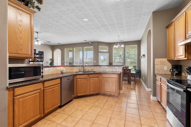 1814 Caroline Ave, Baytown, TX 77523 - kitchen with appliances with stainless steel finishes, a sink, decorative backsplash, arched walkways, and a textured ceiling