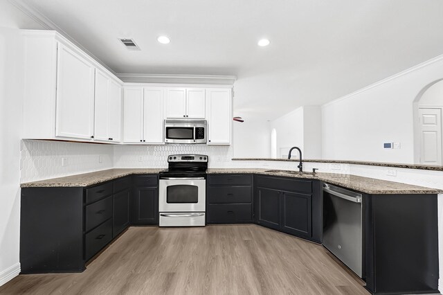 21357 Thurston Crossing Dr, Porter, TX 77365 - kitchen featuring appliances with stainless steel finishes, a sink, light wood finished floors, white cabinets, and ornamental molding