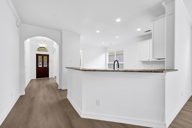 21357 Thurston Crossing Dr, Porter, TX 77365 - kitchen with arched walkways, wood finished floors, white cabinets, baseboards, and dark stone counters