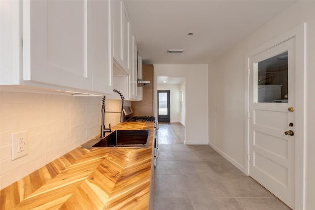 1730 Wakefield Dr, Houston, TX 77018 - kitchen featuring wooden counters, white cabinetry, gas range oven, backsplash, and baseboards
