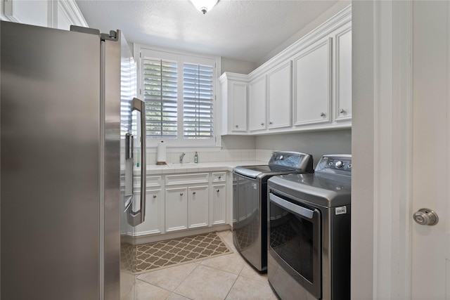 9611 Stonebridge Pl, Tomball, TX 77375 - washroom featuring independent washer and dryer, cabinet space, light tile patterned floors, and a textured ceiling