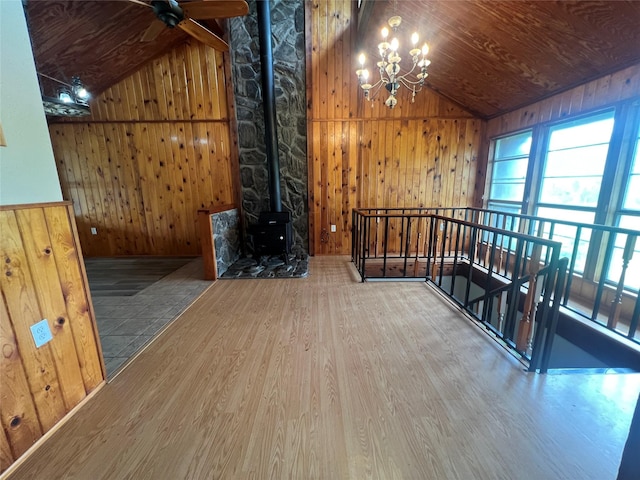 10011 Schanzer Rd, Hitchcock, TX 77563 - unfurnished living room featuring vaulted ceiling, wood finished floors, wood walls, a chandelier, and a wood stove