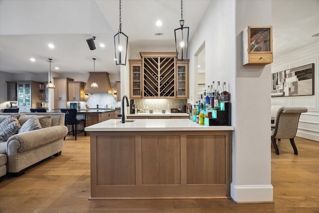 4019 Drummond St, Houston, TX 77025 - indoor bar with wall chimney range hood, recessed lighting, backsplash, light wood-type flooring, and hanging light fixtures