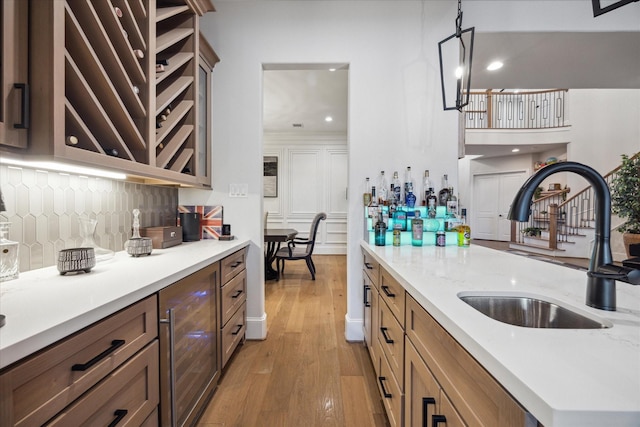 4019 Drummond St, Houston, TX 77025 - kitchen featuring wine cooler, a sink, light wood-type flooring, decorative backsplash, and hanging light fixtures