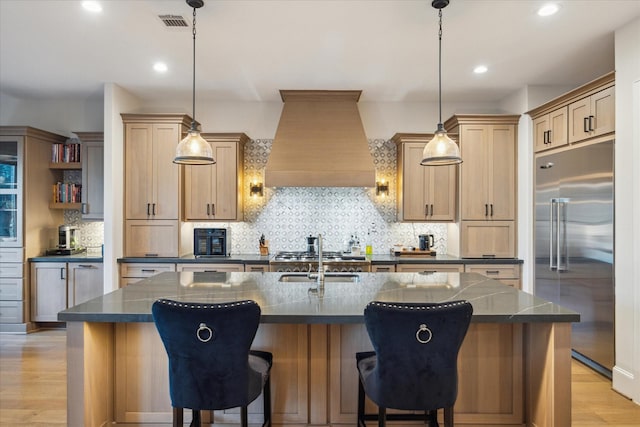 4019 Drummond St, Houston, TX 77025 - kitchen featuring stainless steel built in fridge, custom exhaust hood, light wood finished floors, backsplash, and a center island with sink
