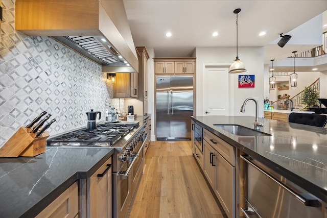 4019 Drummond St, Houston, TX 77025 - kitchen featuring high end appliances, a sink, wall chimney exhaust hood, light wood-style floors, and tasteful backsplash