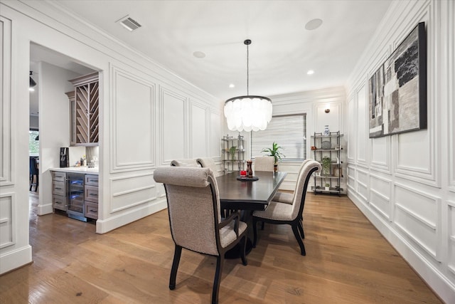 4019 Drummond St, Houston, TX 77025 - dining area with beverage cooler, a decorative wall, a chandelier, a dry bar, and light wood finished floors