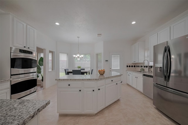 11943 Natural Bridges Ln, Sugar Land, TX 77498 - kitchen featuring appliances with stainless steel finishes, a chandelier, recessed lighting, white cabinets, and a center island